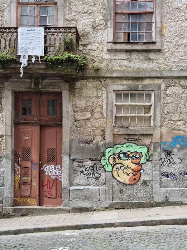 "Cheerful Cartoon Character on Weathered Facade" in Porto