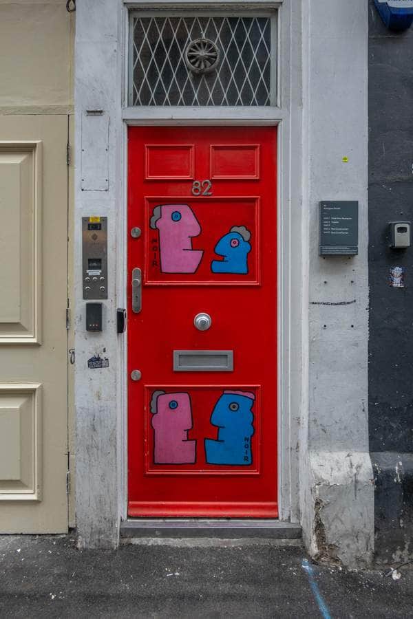 "Playful Figures on Red Door" by Thierry Noir in London