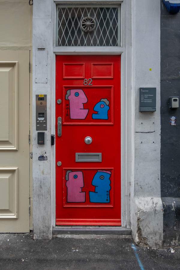 "Playful Figures on Red Door" by Thierry Noir in Shoreditch, London